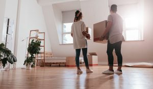 a couple moving into a house carrying boxes