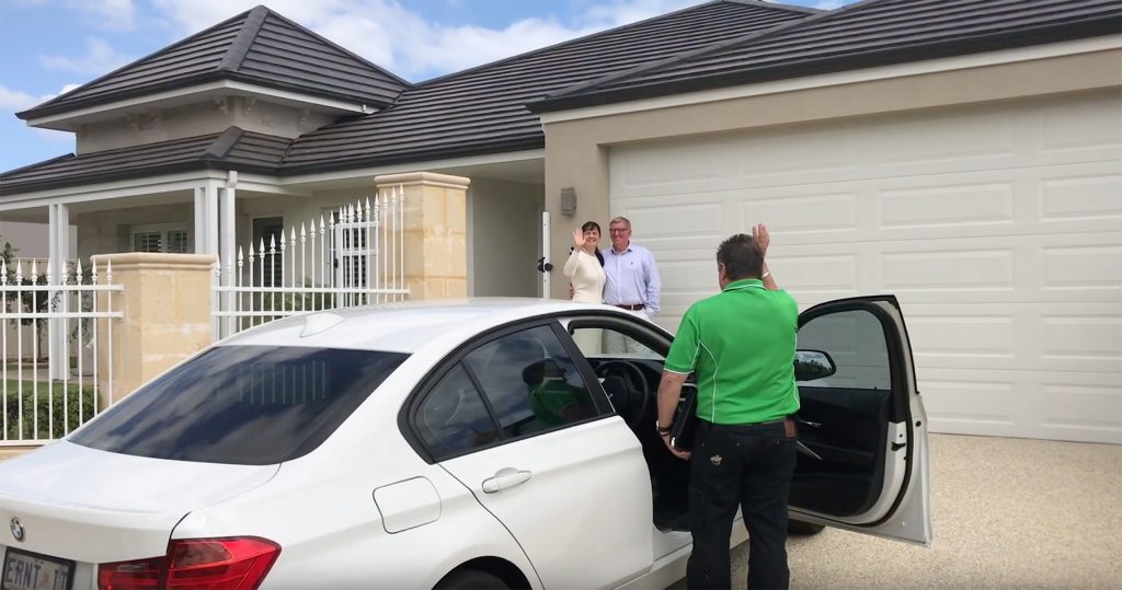 A couple standing in their drive way waving goodbye to Jerry Gibb, their Mobile Mortgage broker after signing the deal on their first home loan to buy their very own house.